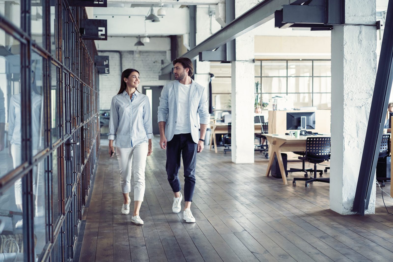 Zwei Menschen gehen durch ein helles Loft-Büro